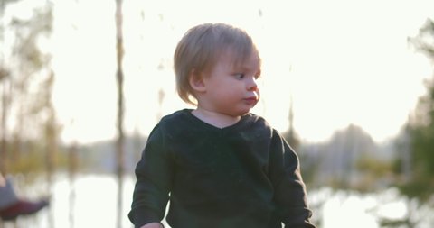 Static, slow motion shot of a little boy pointing, in a finnish forest, on a sunny spring day, in Vaasa, Ostrobothnia, Finland