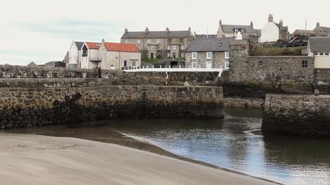 Portsoy Harbour lady walks along harbour wall