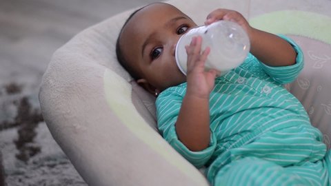 7 month old happy baby drinking milk from bottle right aligned