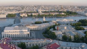 Aerial video of center of Saint Petersburg at sunset, Russia, Old Stock Exchange building, Rostral columns, boats on the Neva river, bridges, Admiralty building, Isaac cathedral
