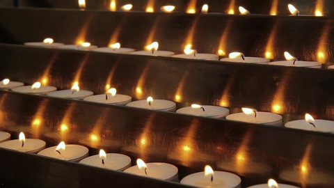 Votive prayer candles inside a catholic church on a candle rack