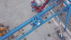 Aerial view of red tower crane standing near the railway in the industrial zone. Clip. Construction and manufacturing processes