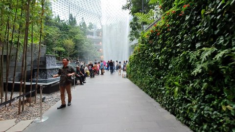 Singapore/Changi - 30th May 2019: 
Tracking Shot of Crowds Transiting to the Indoor Waterfall at The Jewel Changi Airport in Singapore