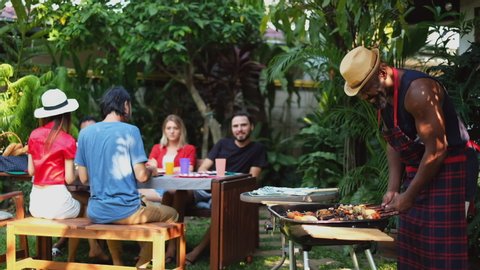 Group of diversity people having barbecue/barbeque party at home outdoor, cooking grilled meat/beef for lunch, happy friends party lifestyle concept
