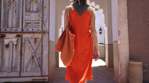 Stunning woman in bright dress exploring Moroccan riad and gardens