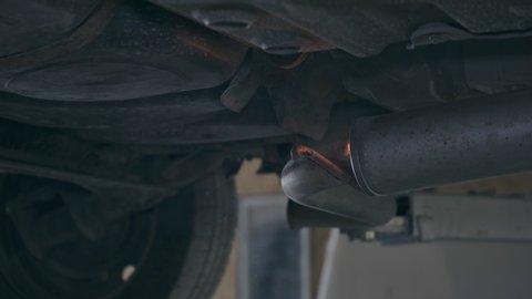 Welder welds car exhaust pipe