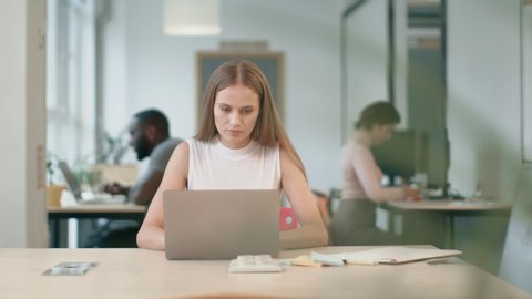 Business woman working at laptop computer at coworking space. Closeup portrait of concentrated lady typing at workplace. Female professional working with documents in office.