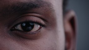 Highly detailed portrait of young mature man staring at camera. Close-up cropped view of beautiful african black man eye on grey background. - Powered by Shutterstock - Get 15% off with code: PIKWIZARD15