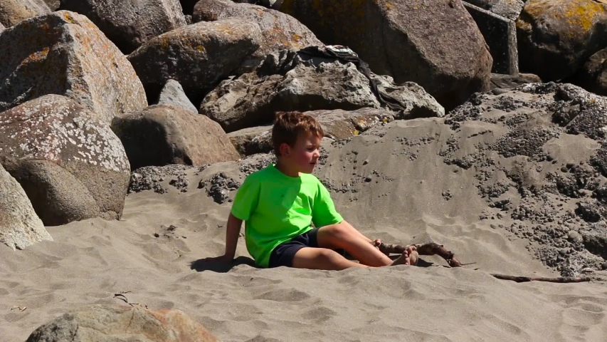 Boy playing with sand and stick at the beach