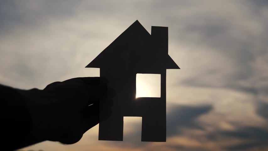 happy family construction house concept. man holding home a paper house in his hands at sunset silhouette sunlight. life ecology video symbol lifestyle