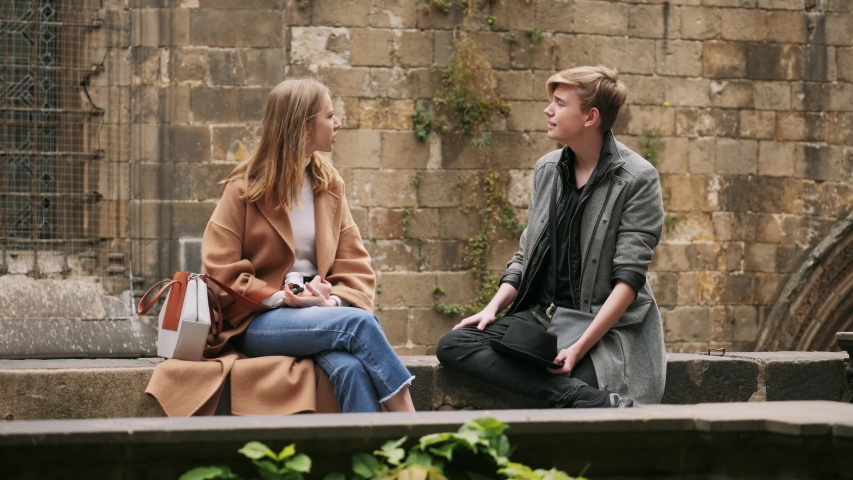 Boy and girl are sitting outdoor and talking.