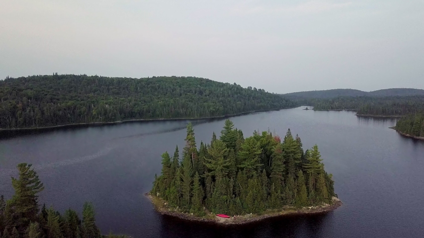 4k Aerial view of Lake Superior and forest landscape in Canada during sunset with amazing orange colours and crashing waves on Coast