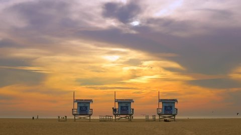 VENICE BEACH, SANTA MONICA, LOS ANGELES, CA - Jun 2019. Silhouettes of lifeguard wooden houses in front of the ocean. Birds and people by the seawater.