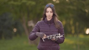 Young Caucasian Female Releasing Propellers on Small Drone Before Flight in Green Park. Blurred Background