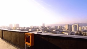 Man in blue wearing a mask climbs on the ledge of a skyscraper looking out over the city in the distance. Landscape and city view from a rooftop. - Powered by Shutterstock - Get 15% off with code: PIKWIZARD15