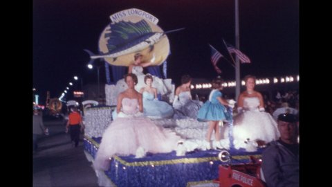 1960s: Women seated on parade float, waving, with young girl standing at front. Miss Delaware waves from convertible in parade. Woman standing on parade float waves.