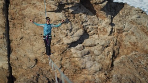 A young woman is on the slackline at high altitude.