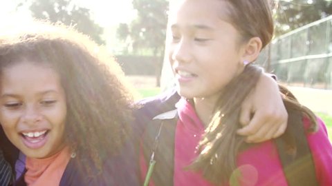 Slow motion sequence as camera pans along line of children hanging out with friends in park.Shot on Sony FS700 at frame rate of 100fps