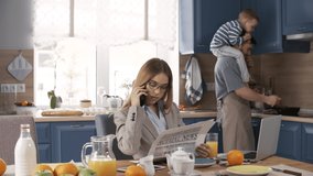 Full shot of glamorous Caucasian businesswoman in suit talking on phone and reading newspaper while waiting for breakfast, and husband with 3-year-old son cooking and trying to attract her attention - Powered by Shutterstock - Get 15% off with code: PIKWIZARD15