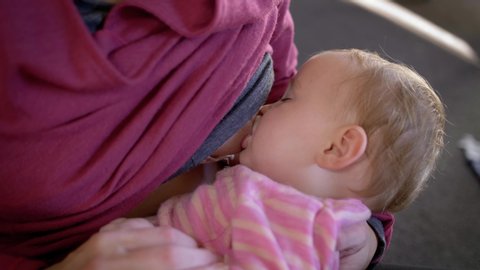 Closeup shot of a newborn child in a pink onesie breastfeeding