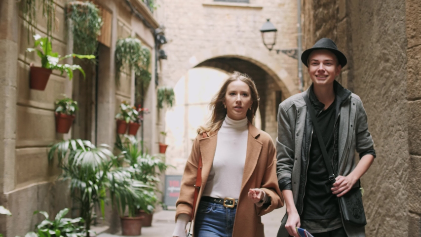 Beautiful and style friends walking with map and camera through tight street.