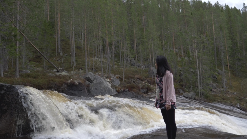 Girl stands beside a flowing river