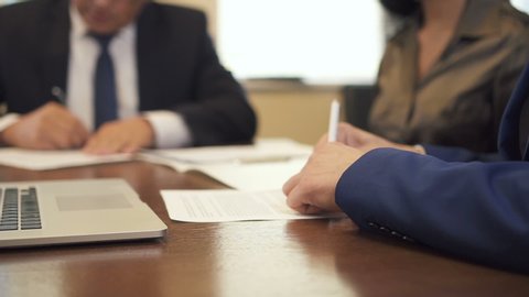Entrepreneur and mature businessman signing contract on office desk. Businesswoman taking document and business partners shaking hands. Slow motion.