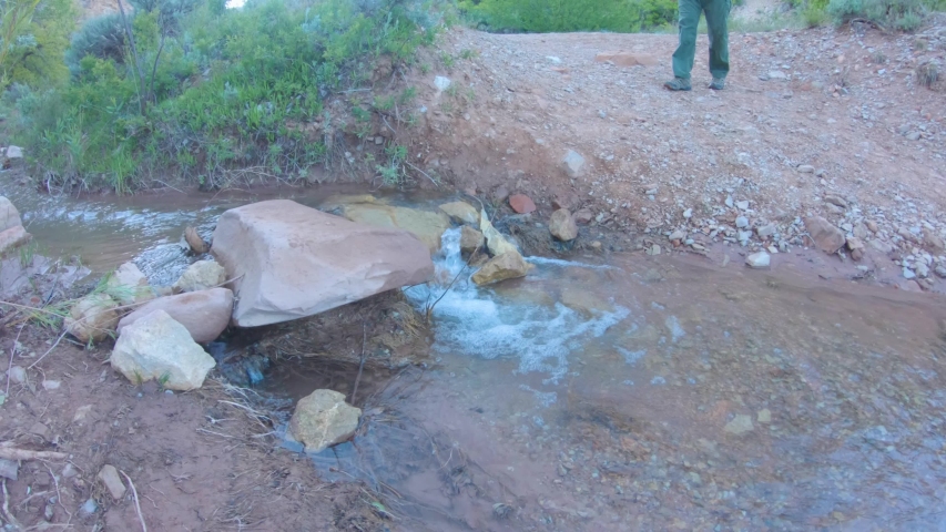 Man carefully steps across a mountain creek