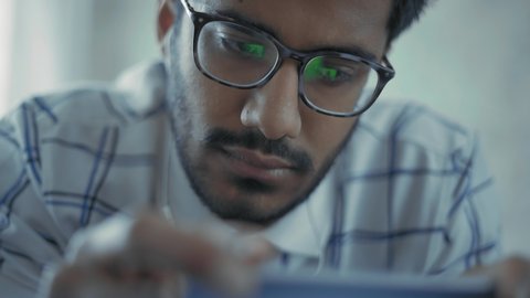 Close-Up, Indian Guy with Glasses Watching Music Video in Headphones on Smartphone