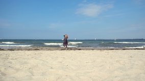 Slow motion video of running girl playing on the beach with waves and sand