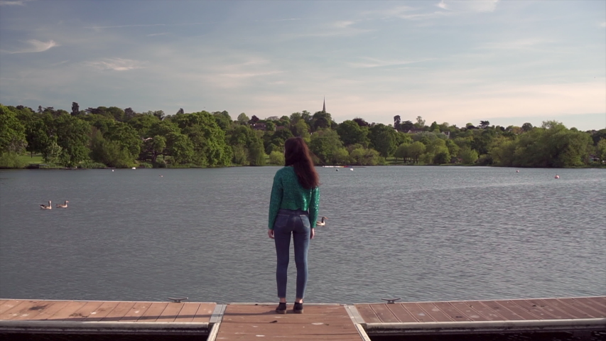 Gorgeous Italian fashion model posing in her outfit in front of a lake in London at golden hour. Fashion and beauty concept. Zoom in Shot