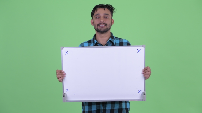 Stressed young bearded Persian hipster man holding white board