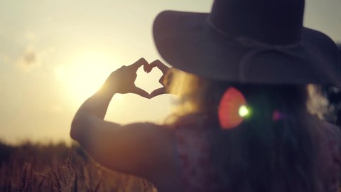 Girl Made Love Heart From Finger.Woman In Hat Enjoying Sun.Lady Making Heart Shape With Hands. Glare Of Summer Sun On Hands.Sun Rays On Morning Weekend. Vacation Holidays Time.Love Heart Signs Symbols