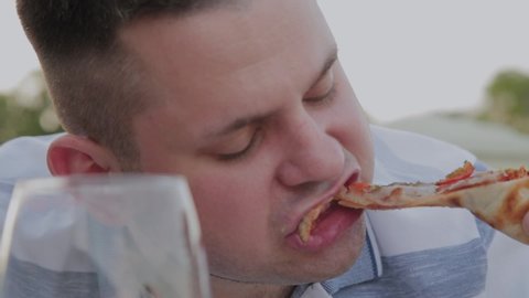 A man eagerly eats junk food in a restaurant.