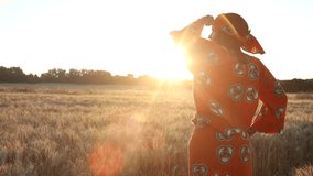 HD Video clip of African woman farmer in traditional clothes standing in a field of crops, wheat or barley, in Africa at sunset or sunrise