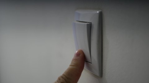 Close Up Man Hand Turning on the Light from a Wall Switch in Office Room