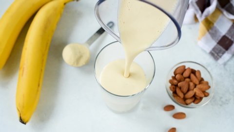 Pouring banana protein shake or smoothie in glass. Healthy eating, healthy lifestyle, weight loss and fitness concept. Vegan, vegetarian food