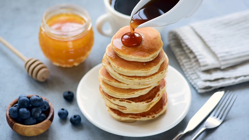 Pouring maple syrup on stack of delicious buttermilk pancakes. Real time footage, tasty food Royalty-Free Stock Footage #1031871515