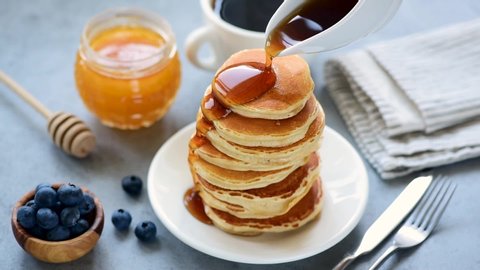 Pouring maple syrup on stack of delicious buttermilk pancakes. Real time footage, tasty food