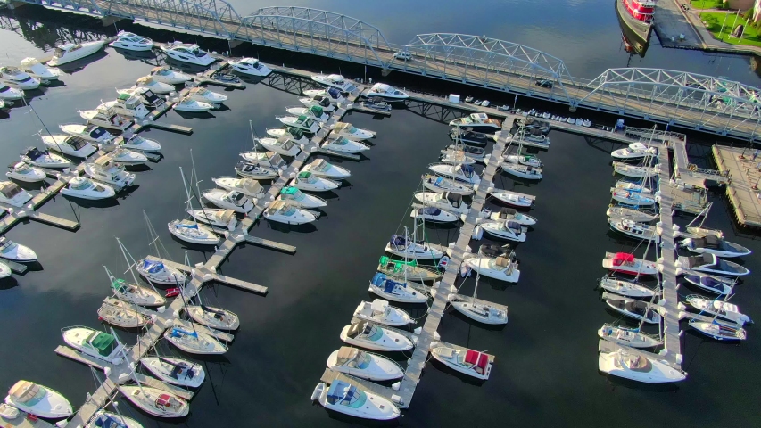 Docks, luxury yachts, sailboats, scenic bridge, aerial view.
