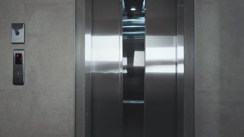 The elevator doors open. Opening the door is an elevator. Metal doors smoothly open and close. Silver new elevator on the 1st floor 4k video.