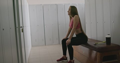 Slender sportswoman in locker room before workout