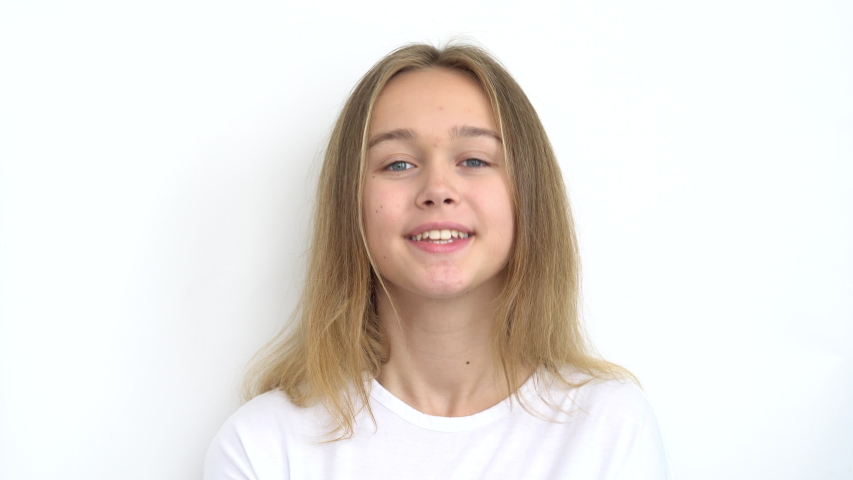 Portrait of a teenage girl with long flowing hair who holds a paper bow tie and jokingly puts it to her neck, then to her hair, then instead of a mustache. Close up.