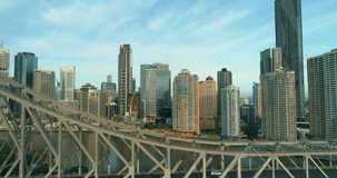 Amazing closeup aerial footage alongside the Story Bridge at sunrise, showing cars travelling and driving, with Brisbane city CBD in the background. 4K slo mo drone