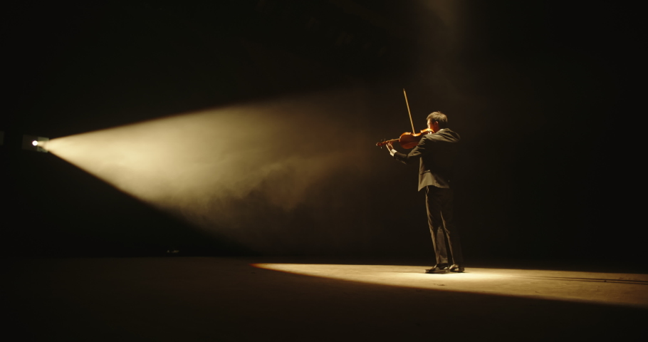 Male violin player having a solo on stage. Professional musician wearing tux is spotted by light on black background 4k footage | Shutterstock HD Video #1031886263