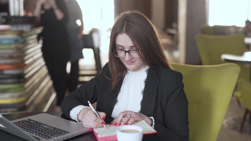 Woman taking notes while working in coffee shop