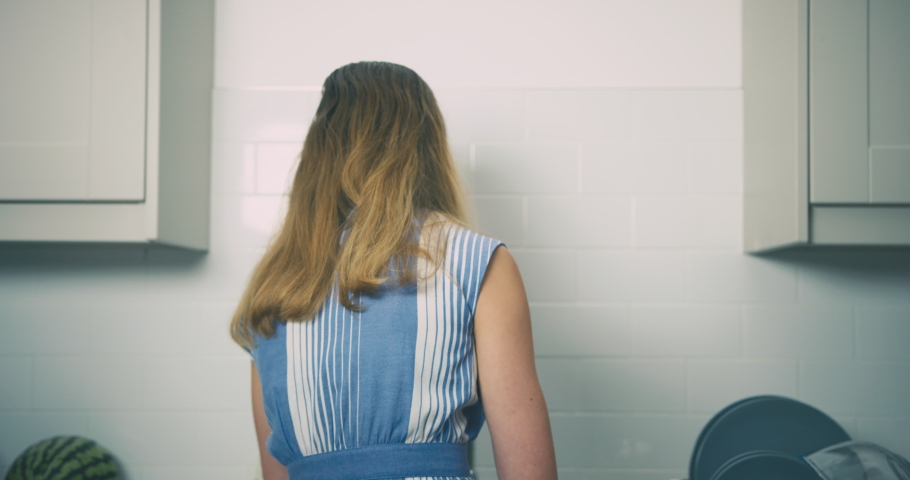 A young woman is doing the dishes at the kitchen sink after dinner in the evening