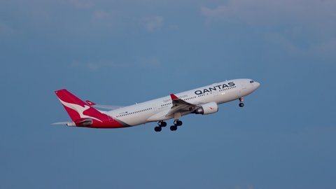Sydney, Australia - May 31, 2019: Qantas Airbus A330 large passenger airliner taking off from Sydney airport after sunset with beautiful pink sky behind. 
