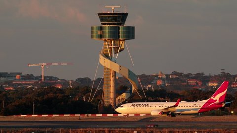 Sydney, Australia - May 31, 2019:  Qantas Boeing 737 taxis in front of the Control tower at Sydney airport with a Singapore airlines Boeing 777.