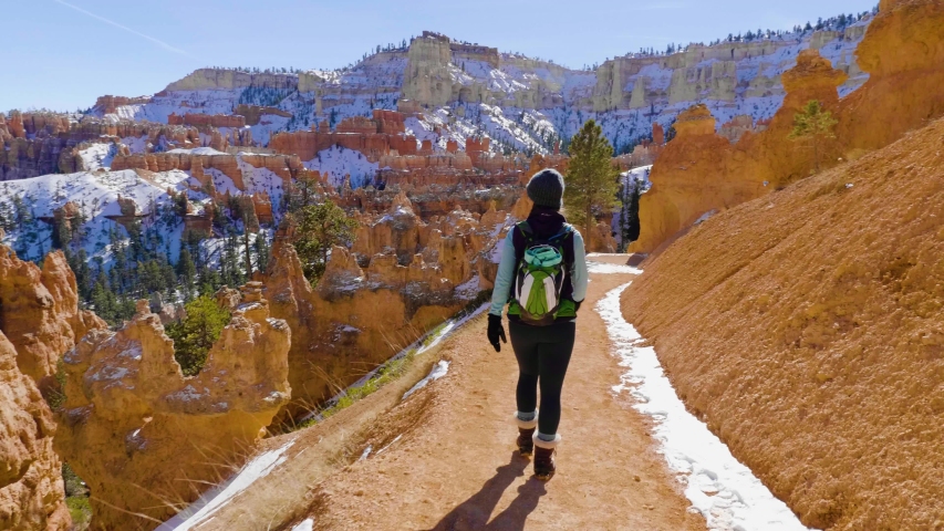 Girl woman hiking with red rocks formation and snow near Bryce Canyon in southern Utah.